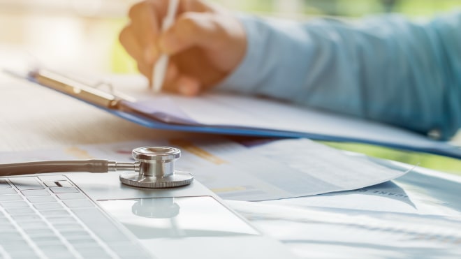 A stethoscope laid on a desk of regulatory documentation.