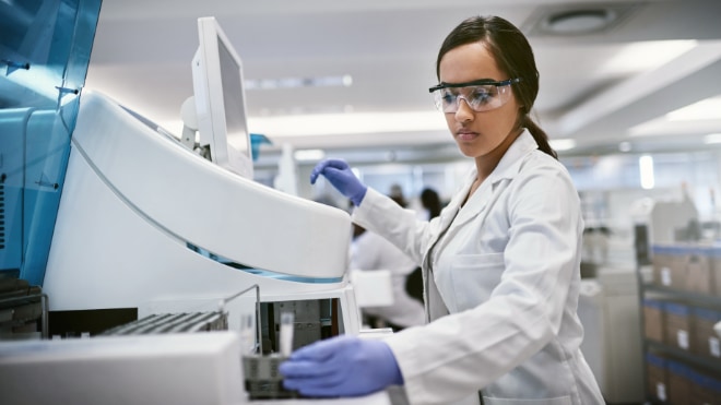 A lab technician enters samples into a machine.